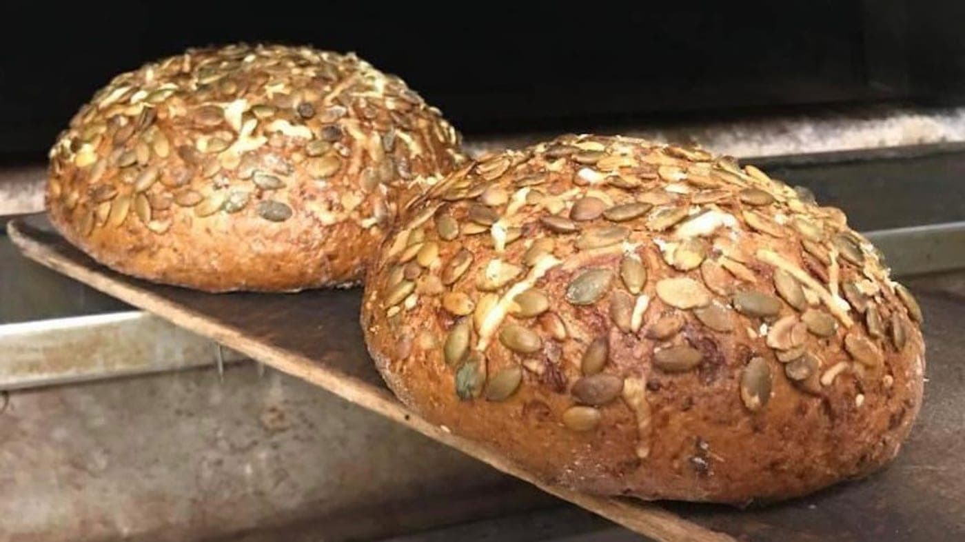 Zwei runde Brote mit knuspriger Kürbiskern-Saaten-Kruste, frisch aus dem Ofen